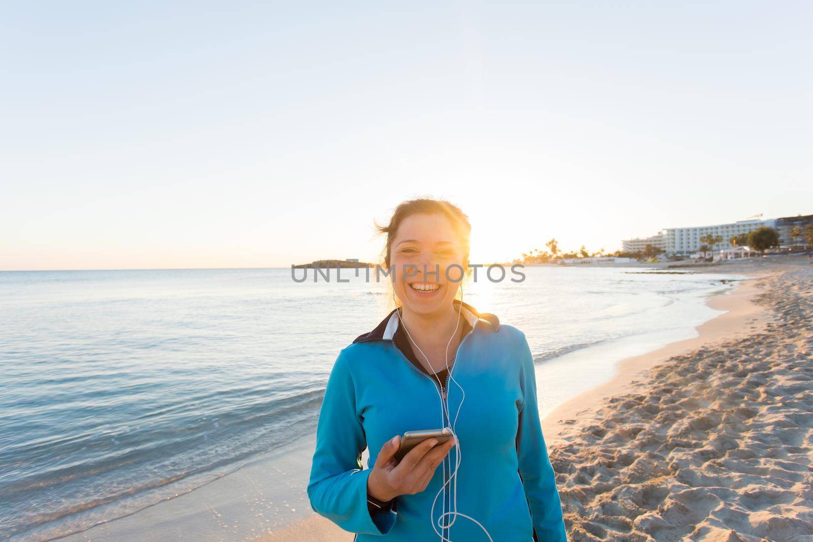 Outdoor sport, fitness gadget and people concept - Smiling female fitness holding smartphone with earphones