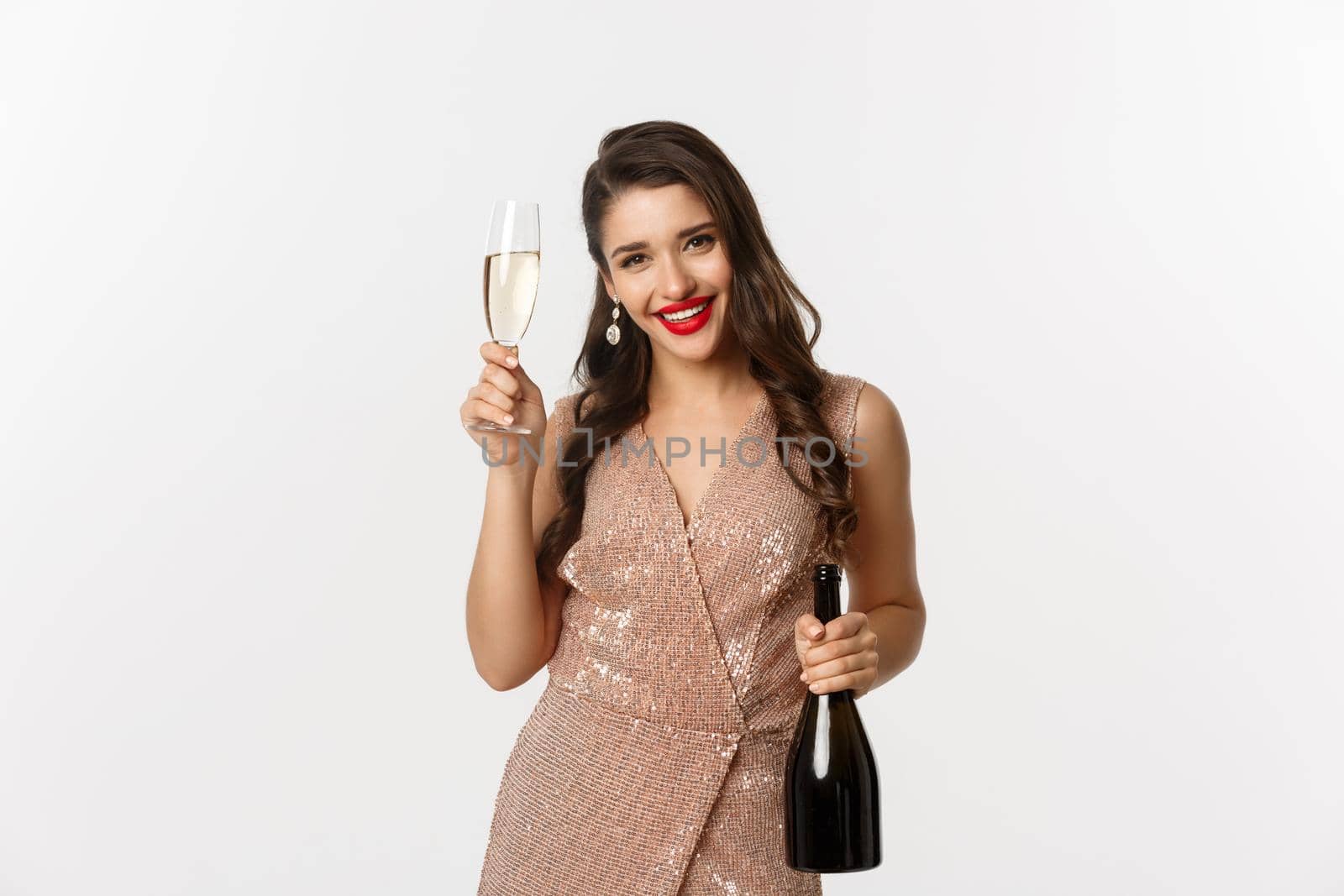 Winter holidays celebration concept. Happy woman on New Year party in luxury dress, drinking champagne and smiling, standing over white background.