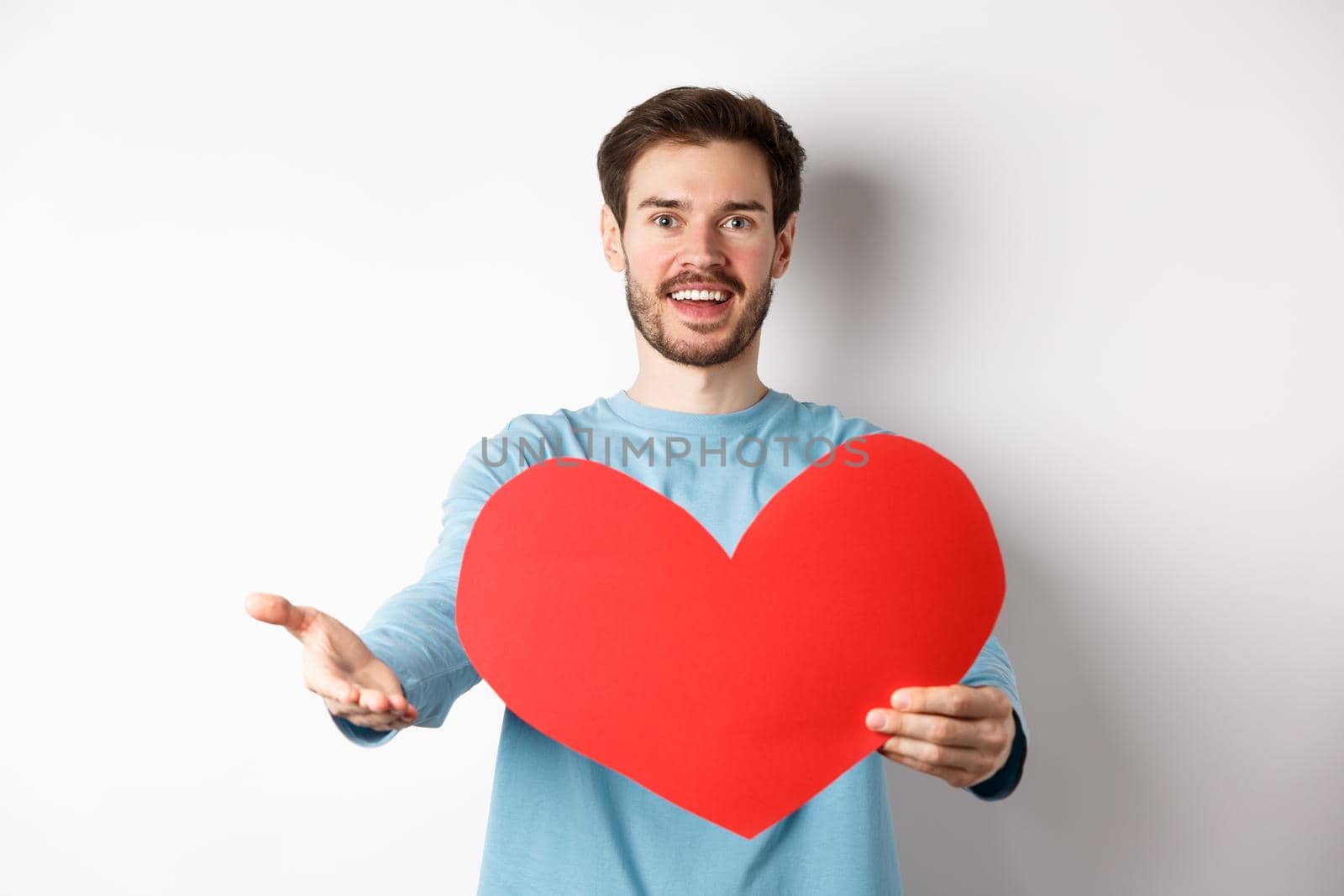 Handsome man in love making confession to you, pointing hand at camera, holding big red heart cutout on valentines day, singing romantic serenade, standing over white background by Benzoix