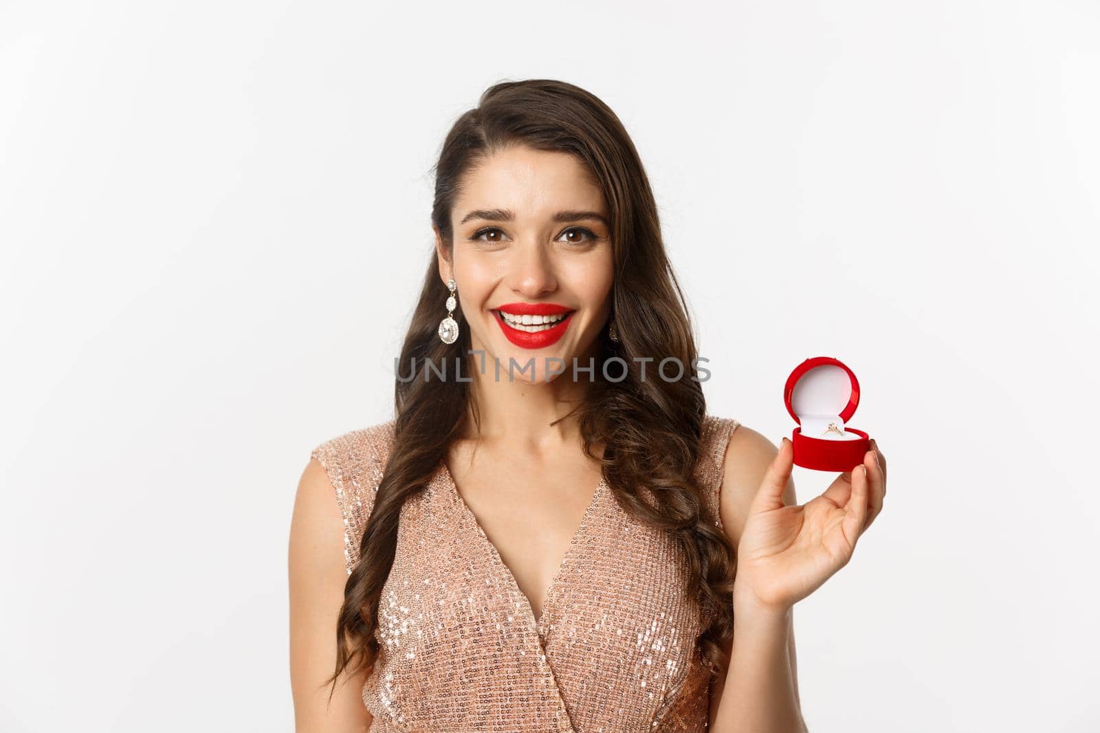 Close-up of beautiful brunette woman showing engagement ring, wearing elegant dress, receive marriage proposal, white background.