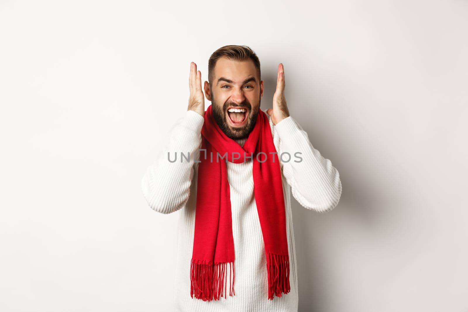 Christmas holidays and New Year concept. Angry man in scream and shout, shaking hands near head with frustrated expression, standing over white background by Benzoix