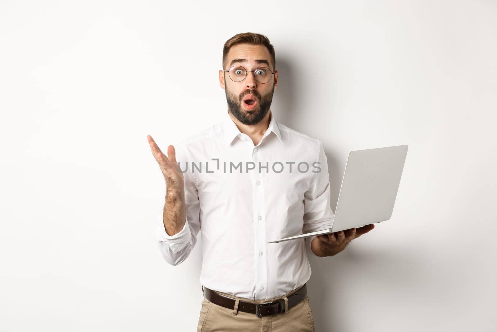 Business. Man holding laptop and looking amazed, surprised with website, standing over white background. Copy space