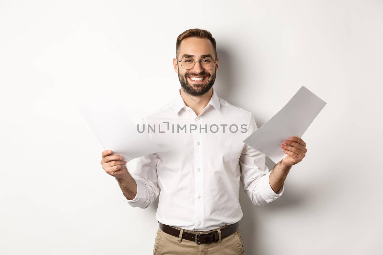 Satisfied boss smiling while holding good report, reading documents, standing over white background.