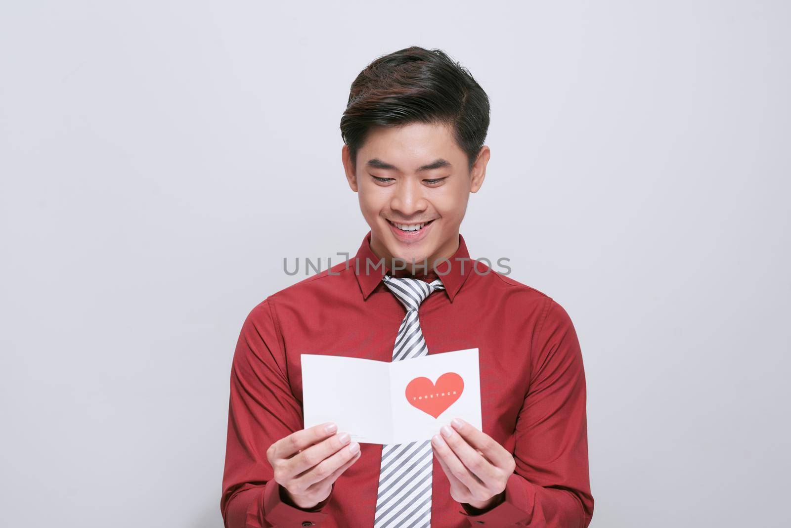 Handsome man with greeting card on light background. Valentine's Day celebration by makidotvn