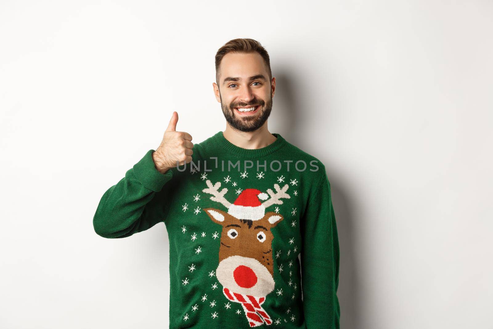 Winter holidays and christmas. Happy bearded man showing thumb up in approval, like something, praise good job, standing over white background.