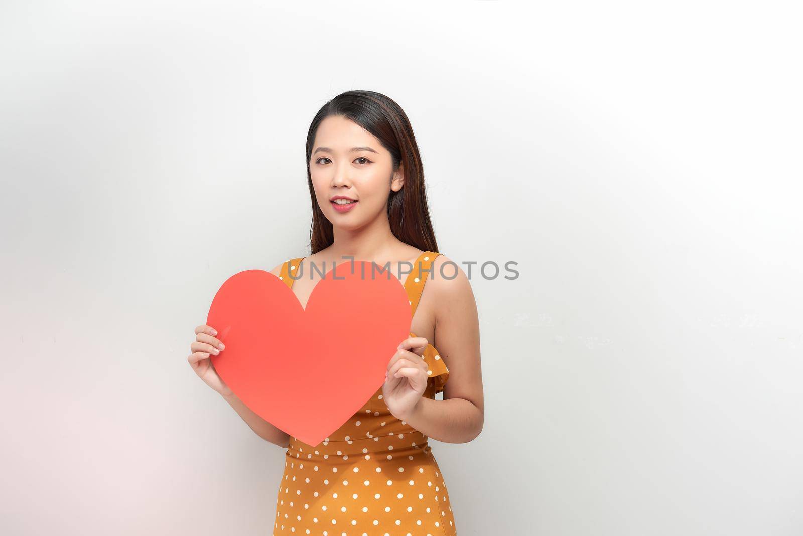 The happy woman holding a heart symbol on the white background