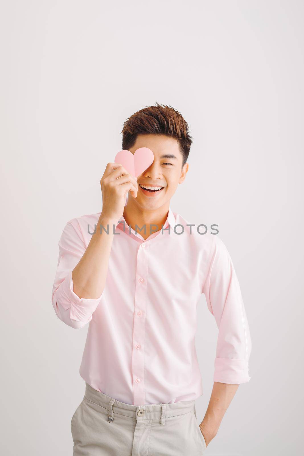 Young handsome asian man reads greeting card with heart shape on white background