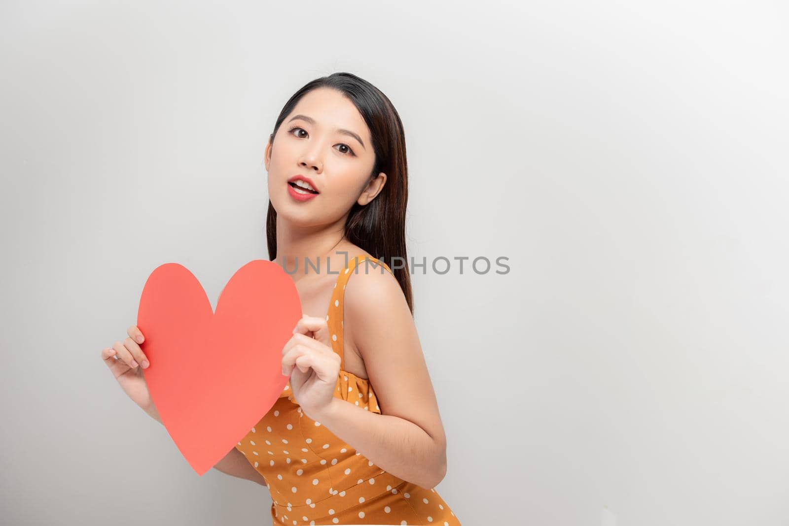 Attractive young asian woman showing red heart on white background