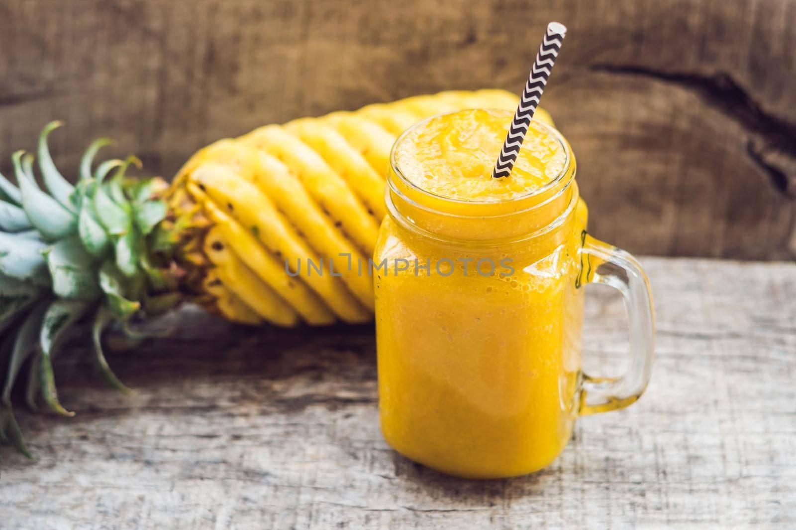 Pineapple smoothie with fresh pineapple on wooden table.