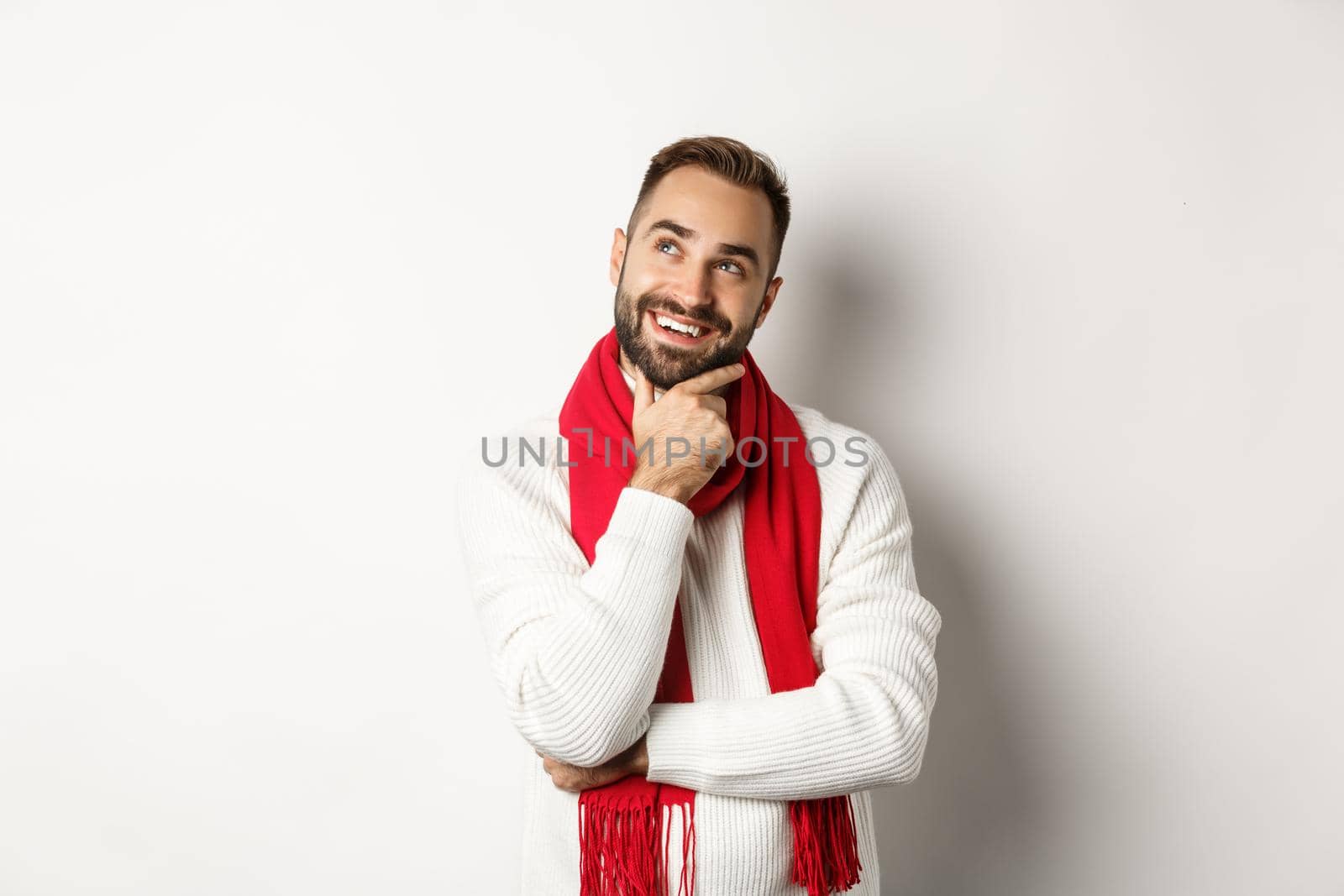 Christmas holidays and celebration concept. Thoughtful boyfriend thinking about gifts, looking at upper left corner and smiling satisfied, pondering new year ideas.