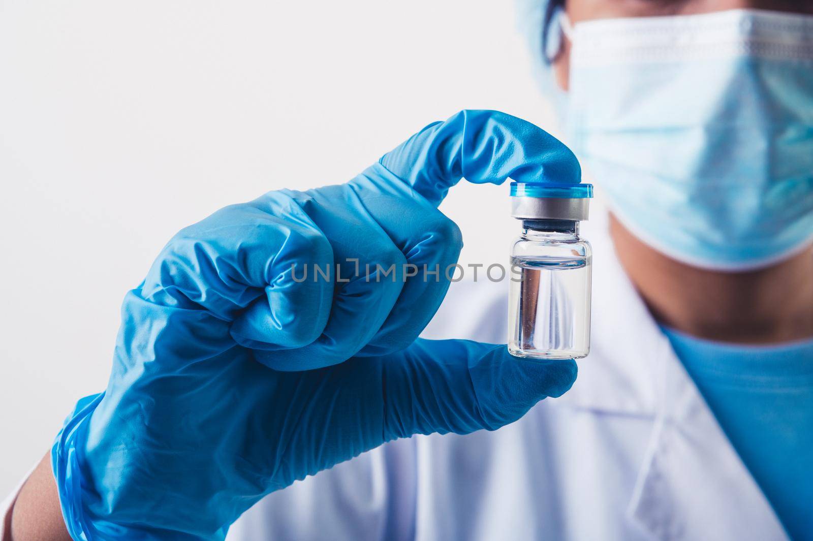 Closeup vial of covid-19 vaccine in hand of professional scientist or doctor in laboratory for treatment with mask gloves and lab coat on white background. Health business and industry concept. by MiniStocker