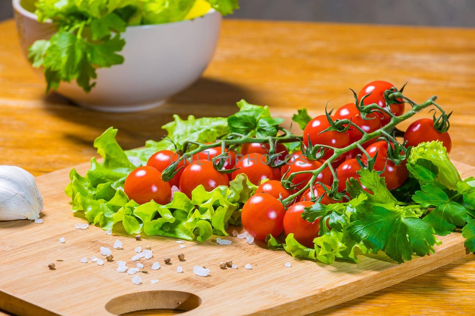 Fresh cherry tomatoes with green salad and garlic on a cutting board. Healthy food concept. Vegetarianism.