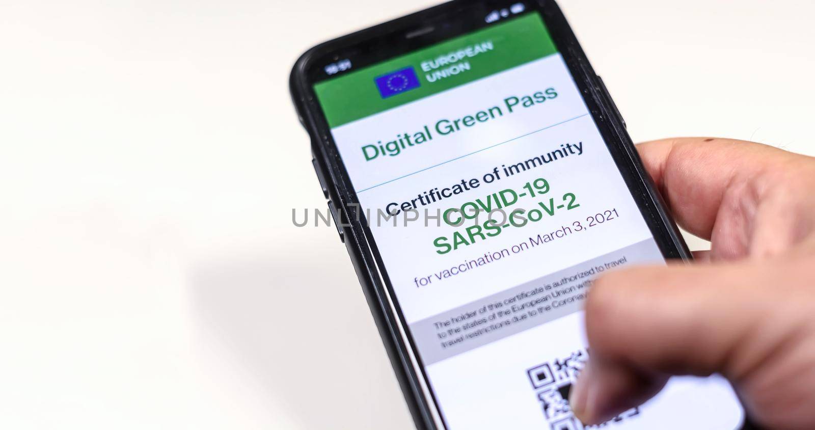 The digital green pass of the european union with the QR code on the screen of a mobile held by a hand on a white background. Immunity from Covid-19. Permit to travel without restrictions.