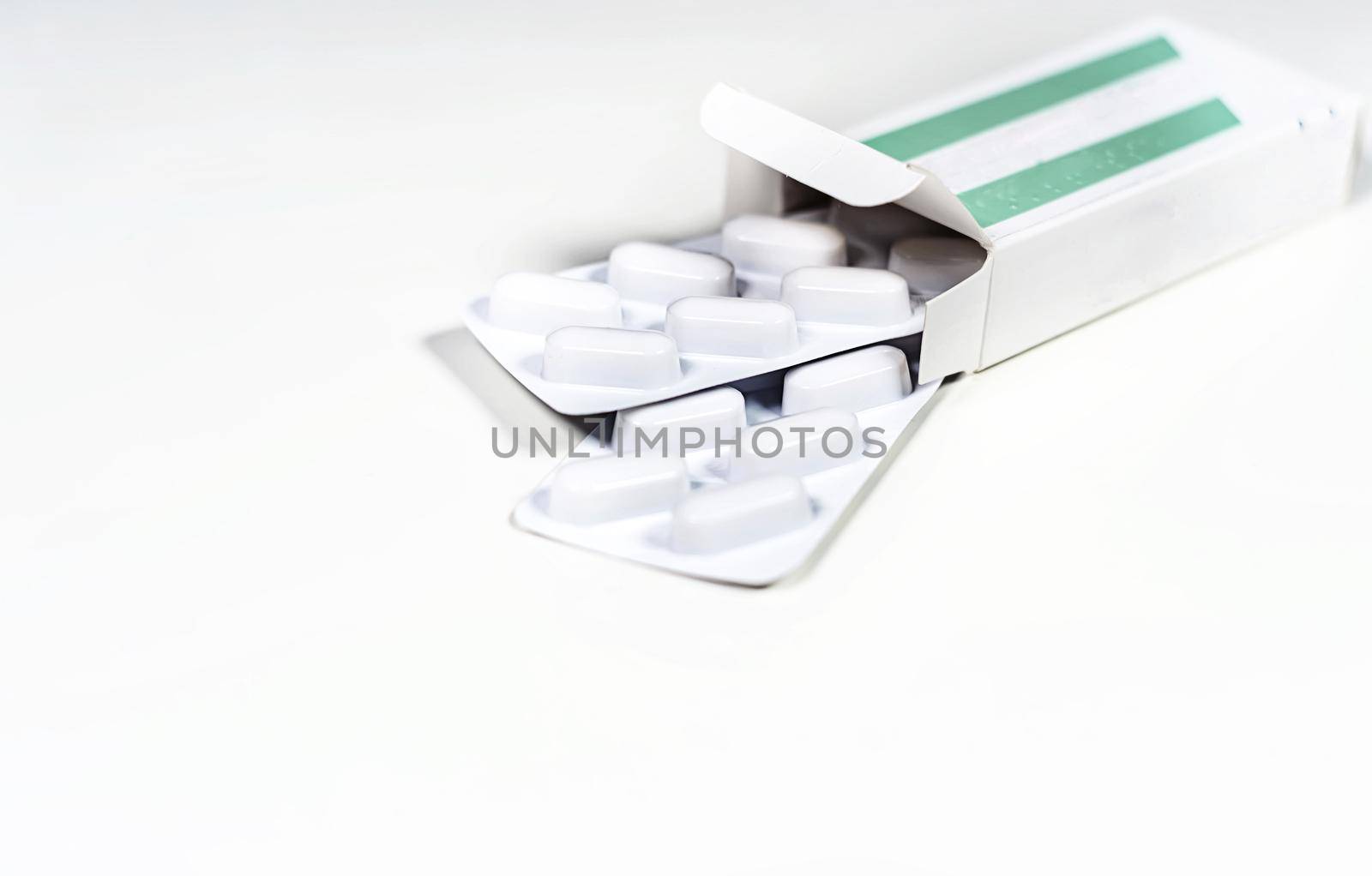 White blister with pills in a green and white box isolated on a white background. Chemistry and medicine. Healthcare and cure concept.