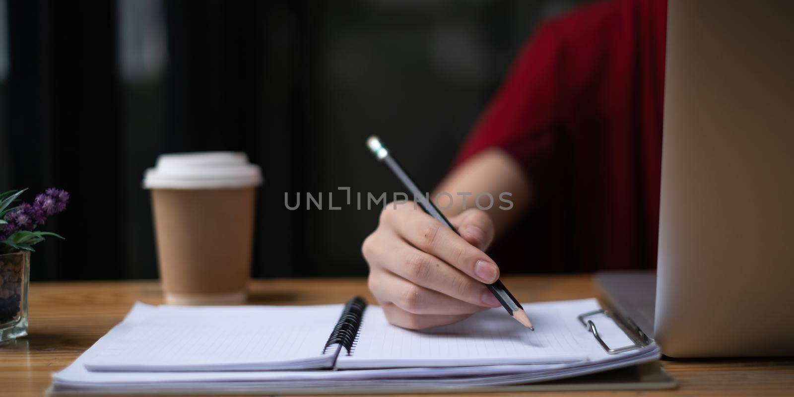 Young female college taking notes and using highlighter. Focused student in online class room. Authentic Education concept by itchaznong