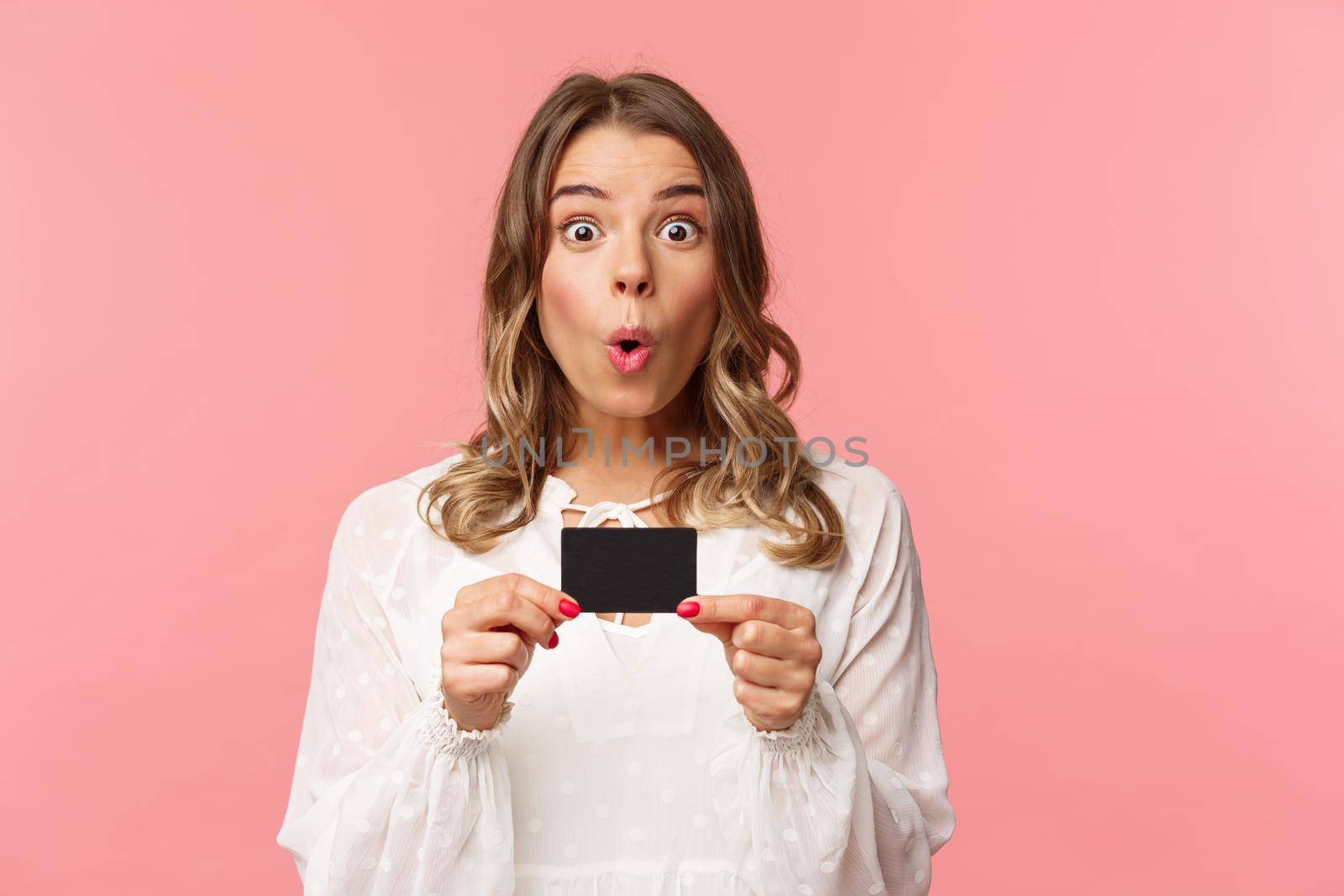 Close-up portrait of excited and amused young girl describe new features of her bank, received new credit card, say wow, folding lips thrilled and amazed, standing pink background by Benzoix
