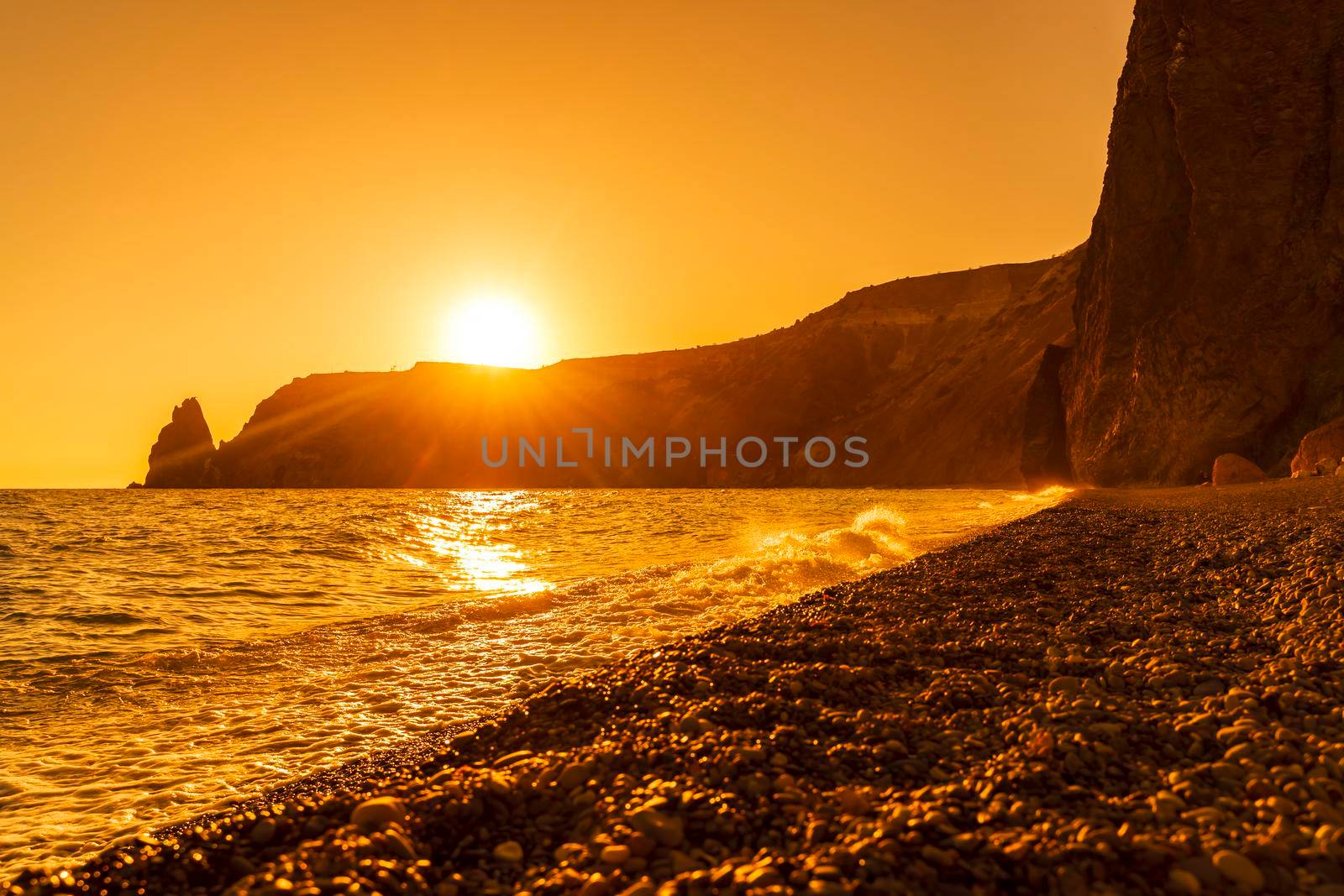 Beautiful golden sunset over the sea, the sun sets behind the mountain. Jasper Beach, Cape Fiolent, no bodies. by Matiunina