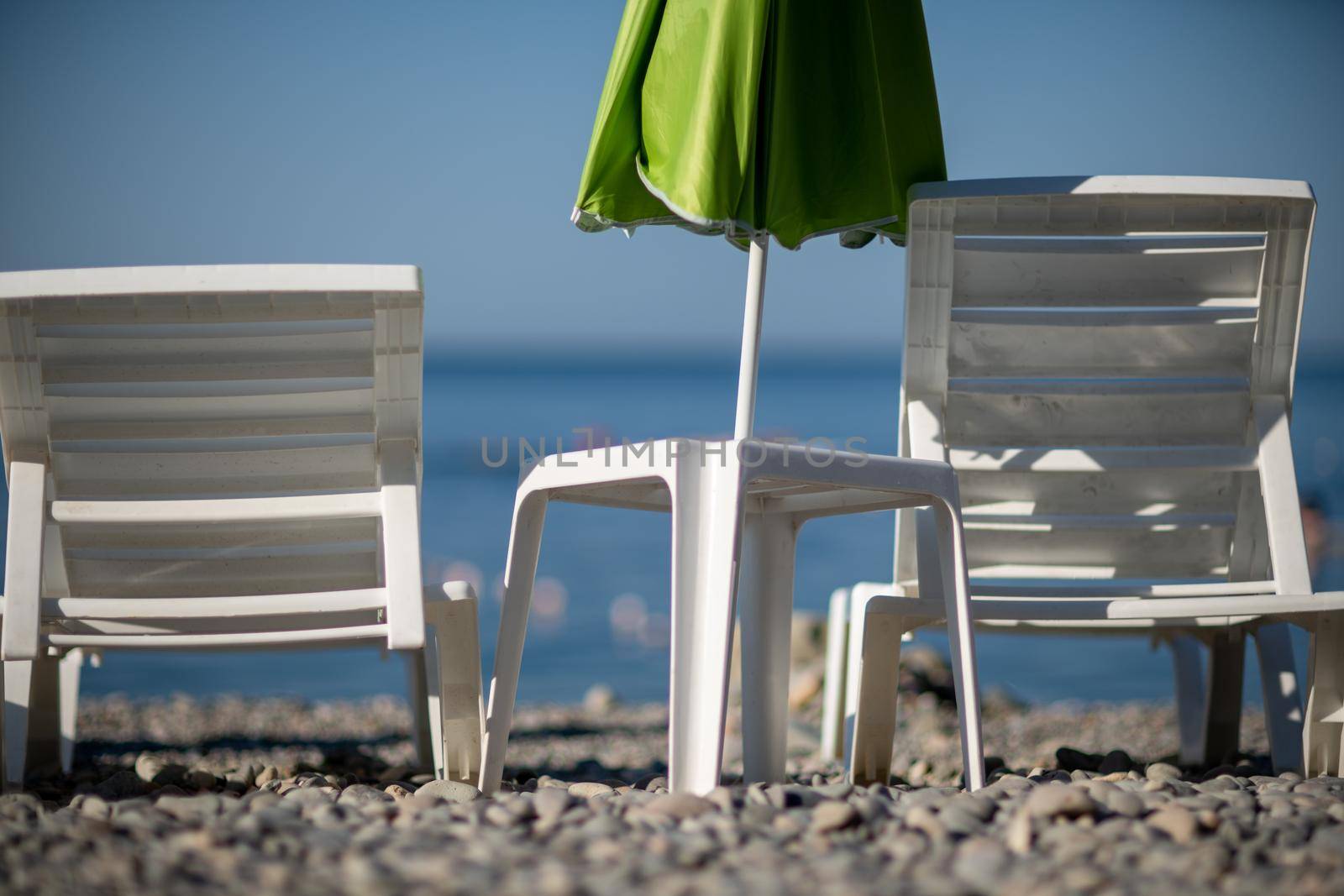 Several white sun loungers and an umbrella on a deserted beach. The perfect vacation concept