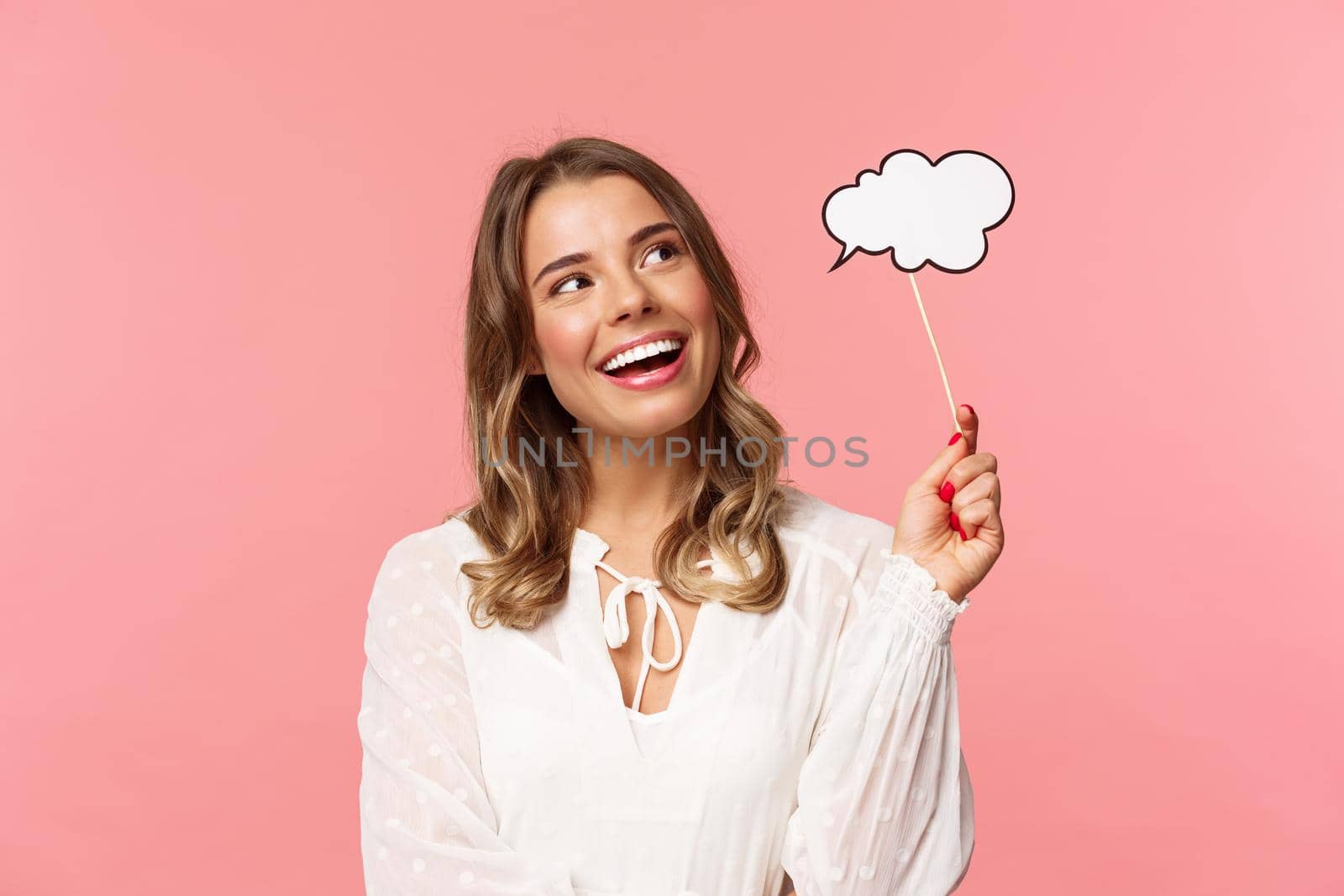 Spring, happiness and celebration concept. Dreamy and lovely blond girl daydreaming, saying something, holding comment cloud stick near mouth as if talking, look away daydreaming.