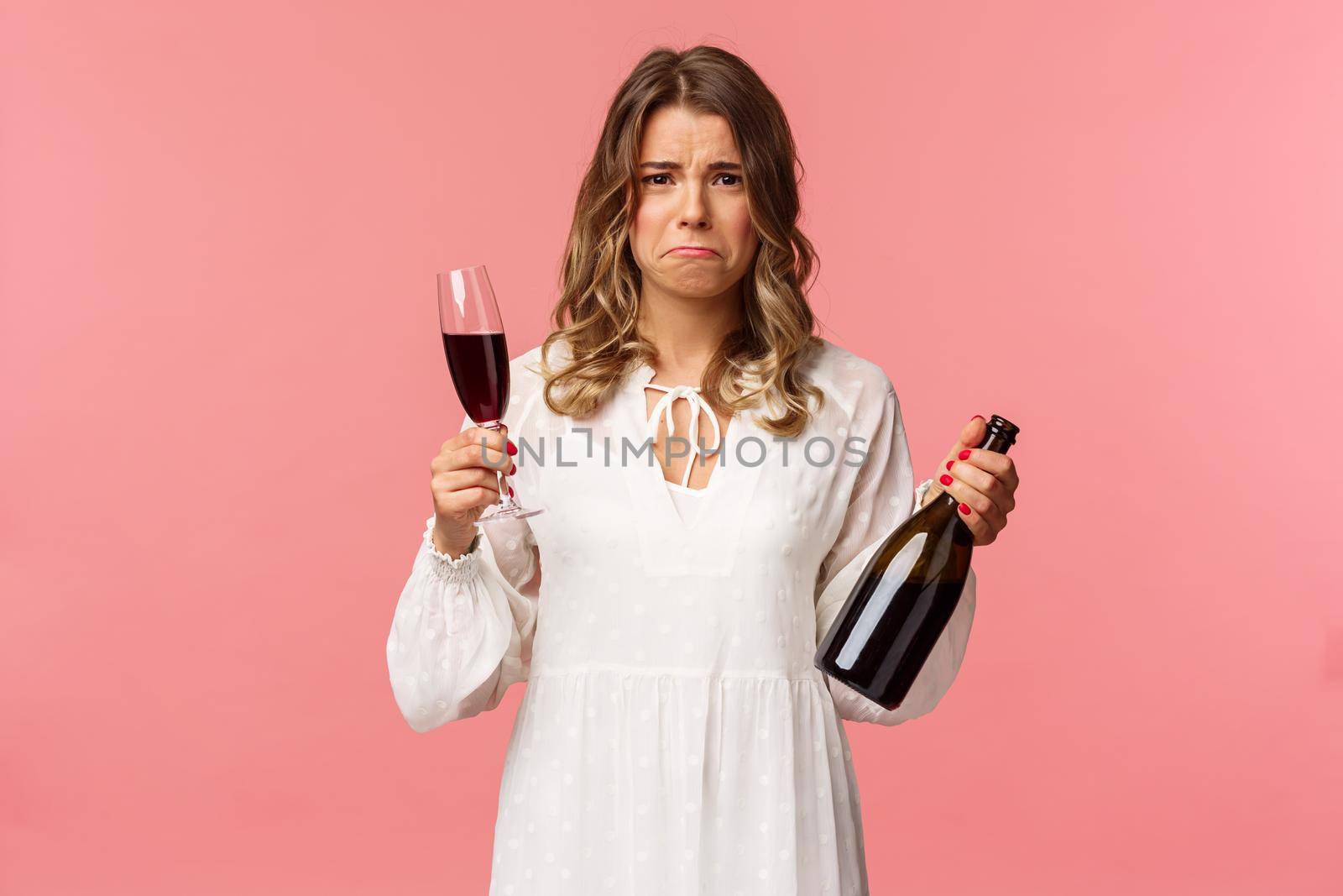 Holidays, spring and party concept. Portrait of upset and whining young blond woman being cheated trying to ease pain with alcohol, holding glass wine and bottle, grimacing want cry, complaining.