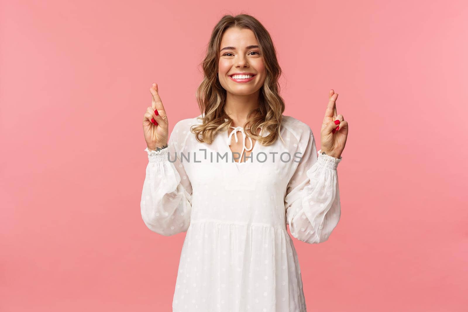 Portrait of optimistic hopeful young blond cute girl, making wish and know it come true, cross fingers good luck, smiling looking camera assertive, praying for dream fulfill, pink background by Benzoix