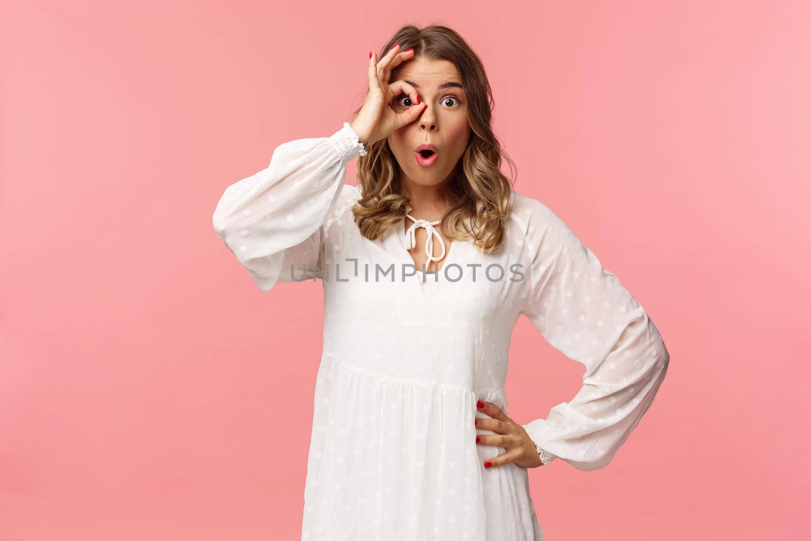 Portrait of amazed and intrigued young blond girl seeing something awesome, look from okay sign with startled excited expression, fold lips say wow, pop eyes at camera, pink background by Benzoix
