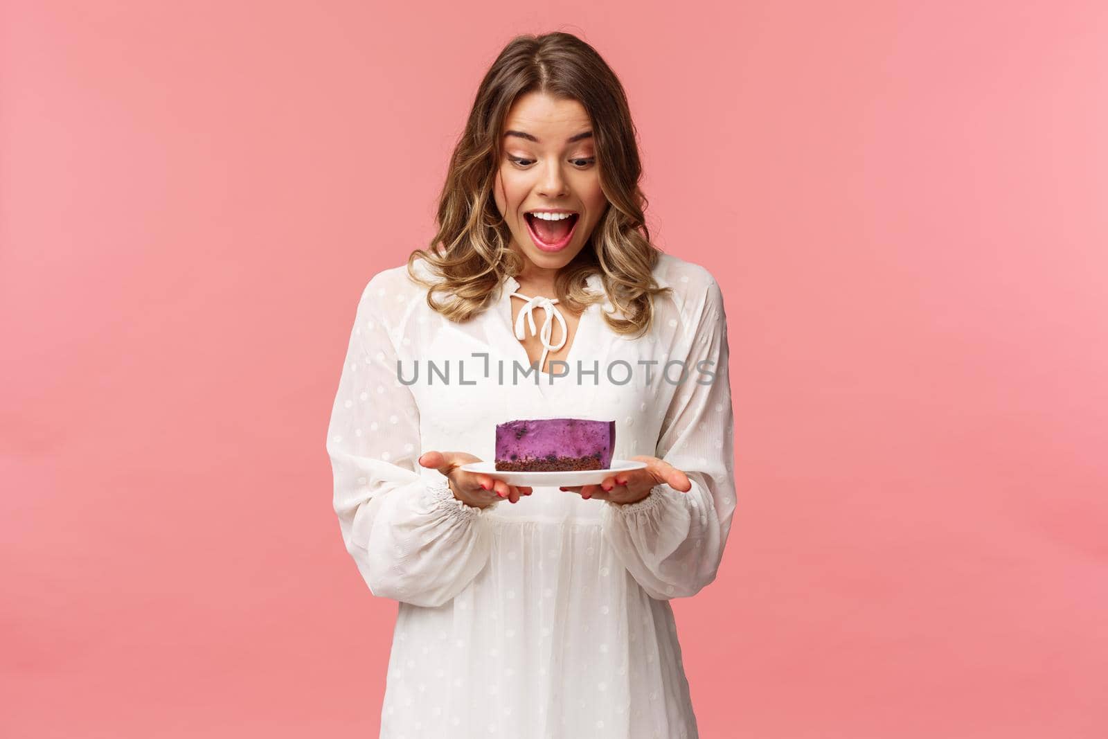 Holidays, spring and party concept. Portrait of happy and excited young blond girl decided start day with sweets, look amazed and cheerful and piece of delicious cake, cant wait to eat it by Benzoix