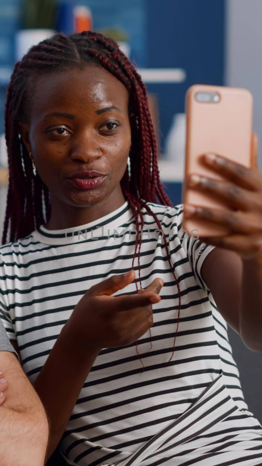 Young interracial couple using online video call conference on smartphone in living room. Modern mixed race lovers talking to friends via internet for remote communication on couch