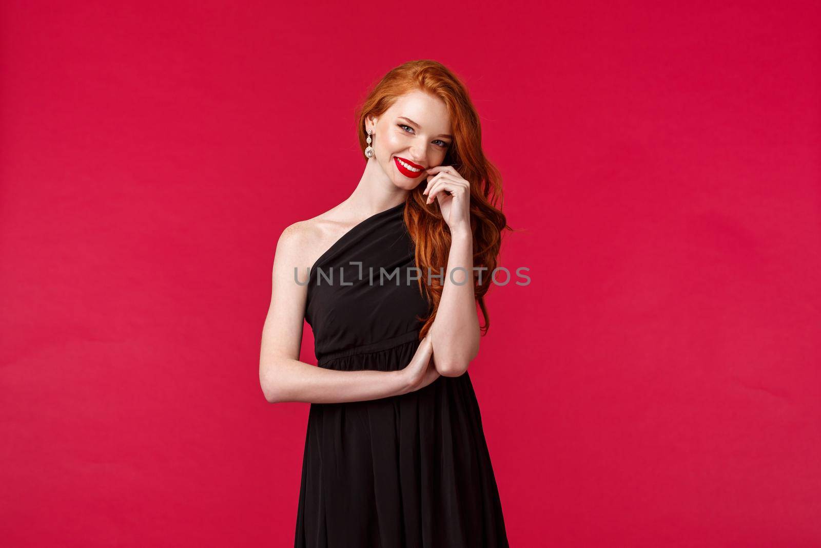 Elegance, fashion and woman concept. Portrait of seducative and sensual woman with ginger hair in elegant evening black dress, attend prom or party, wearing red lipstick, smiling coquettish.