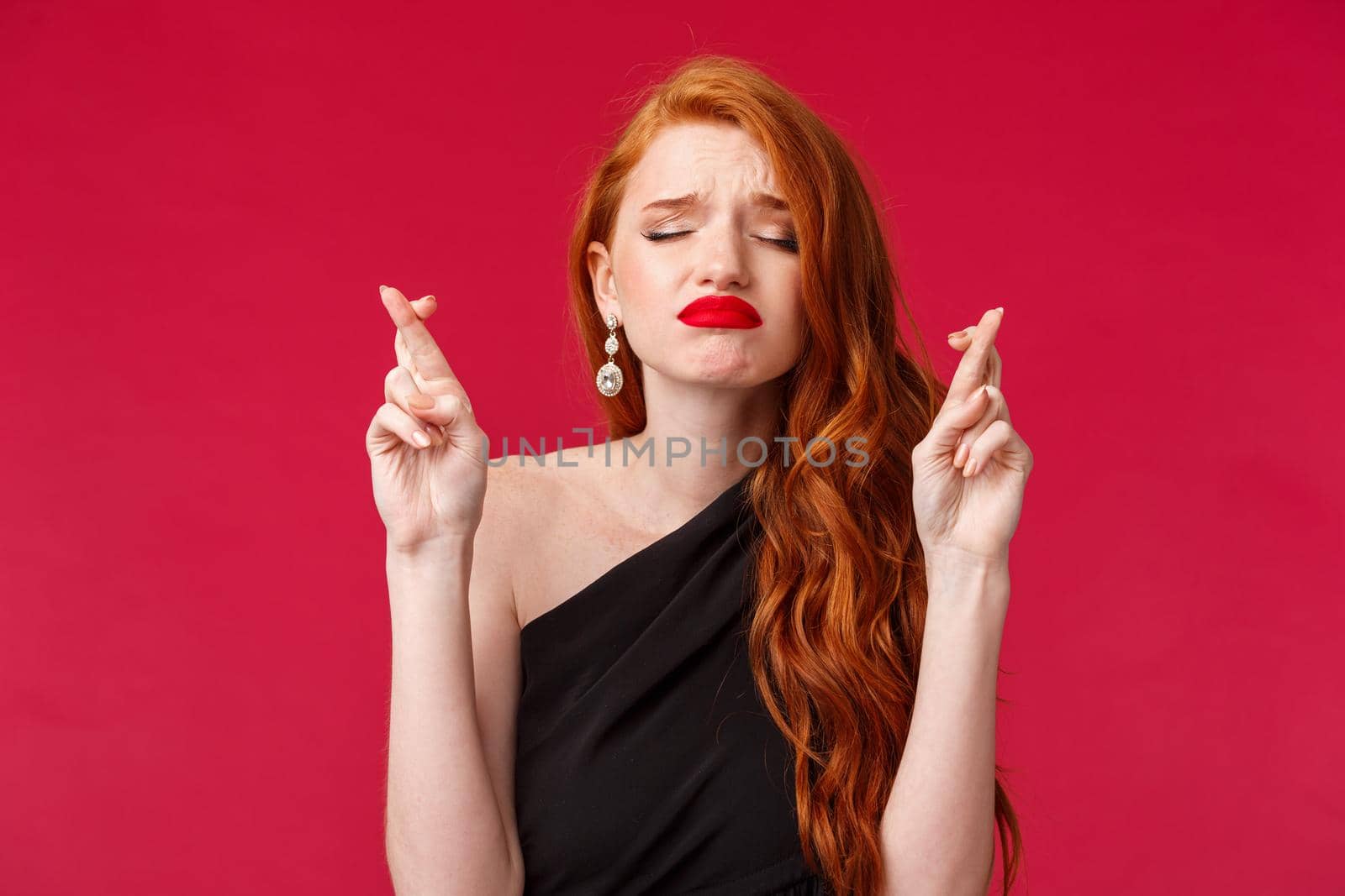 Close-up portrait of hopeful and dreamy, begging young redhead woman cross fingers good luck, praying with closed eyes and worried face, eager dream come true, supplicating.