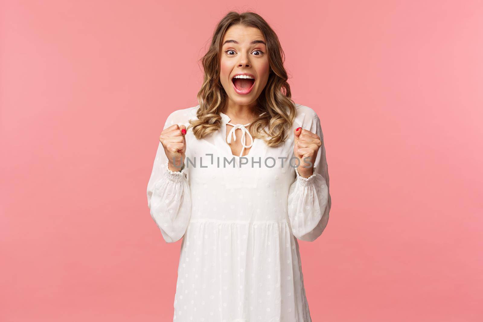 Portrait of surprised lucky hopeful, blond girl winning, hear great news and chanting, gasping open mouth smiling joyful, jumping from happiness and joy, standing pink background by Benzoix