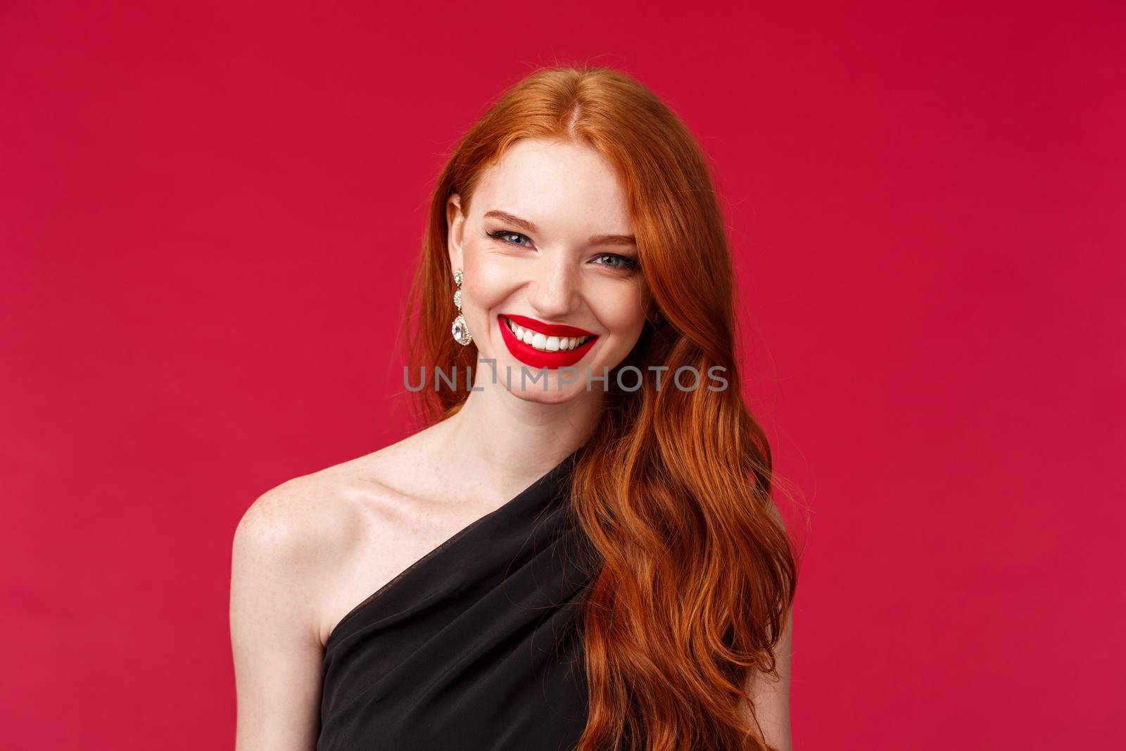 Romance, elegance, beauty and women concept. Elegant good-looking redhead woman in black stylish dress feeling hot and sassy, wear red lipstick, smiling confident, red background by Benzoix