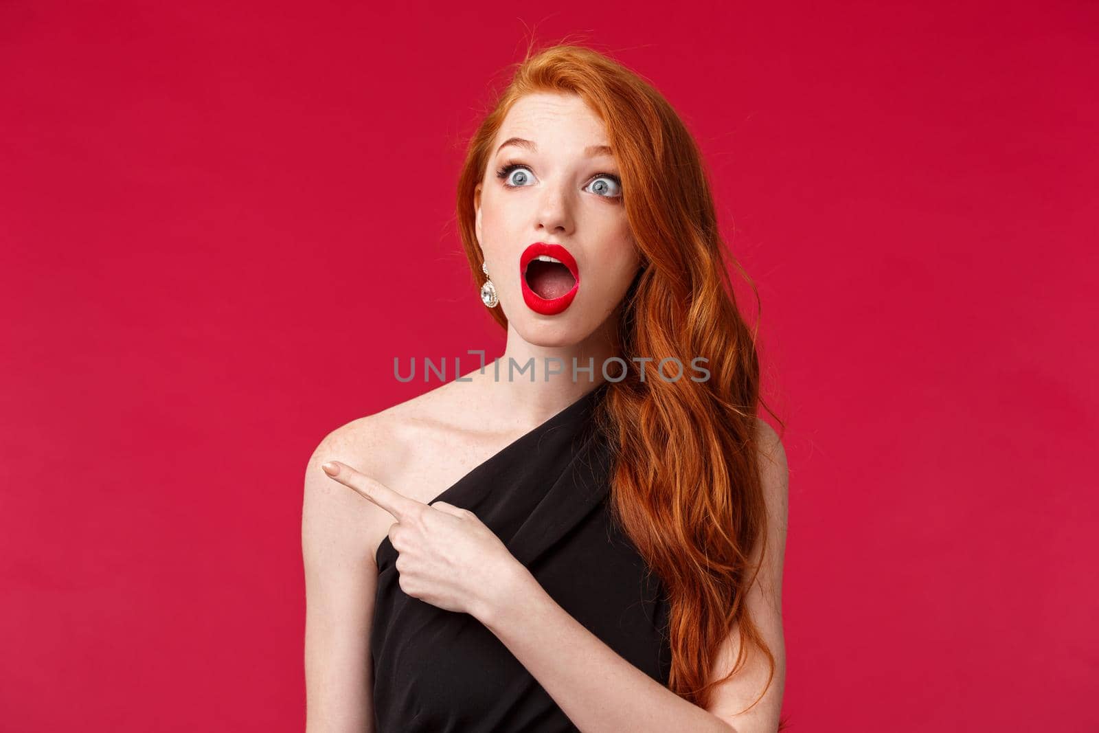 Close-up portrait of speechless impressed redhead woman drop jaw in amazement, seeing something stunning and cool, wear black dress, red lipstick, stare and pointing finger left, red background by Benzoix