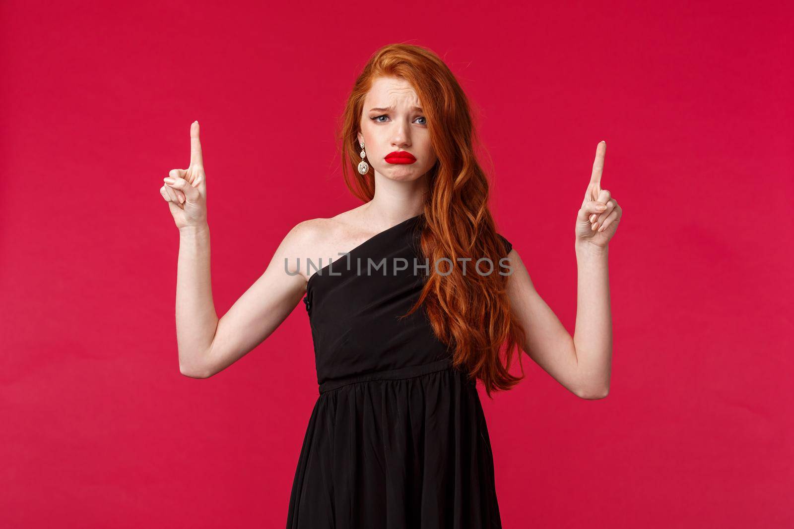 Celebration, events, fashion concept. Portrait of sad and gloomy redhead woman complaining on spoiled and ruined party, wear elegant black dress, evening makeup, frowning and grimacing point up.