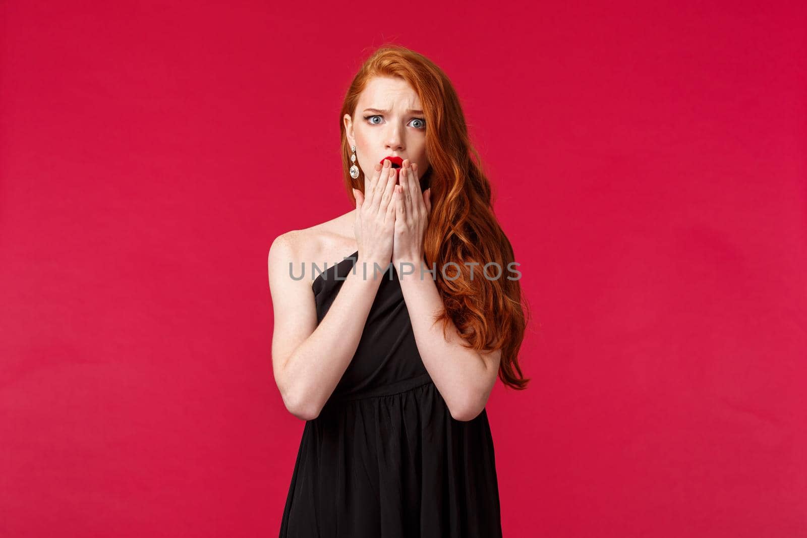 Fashion, luxury and beauty concept. Portrait of shocked and worried, young concerned woman with ginger hair, black dress, see bad thing happened at party, gasping and frowning alarmed by Benzoix