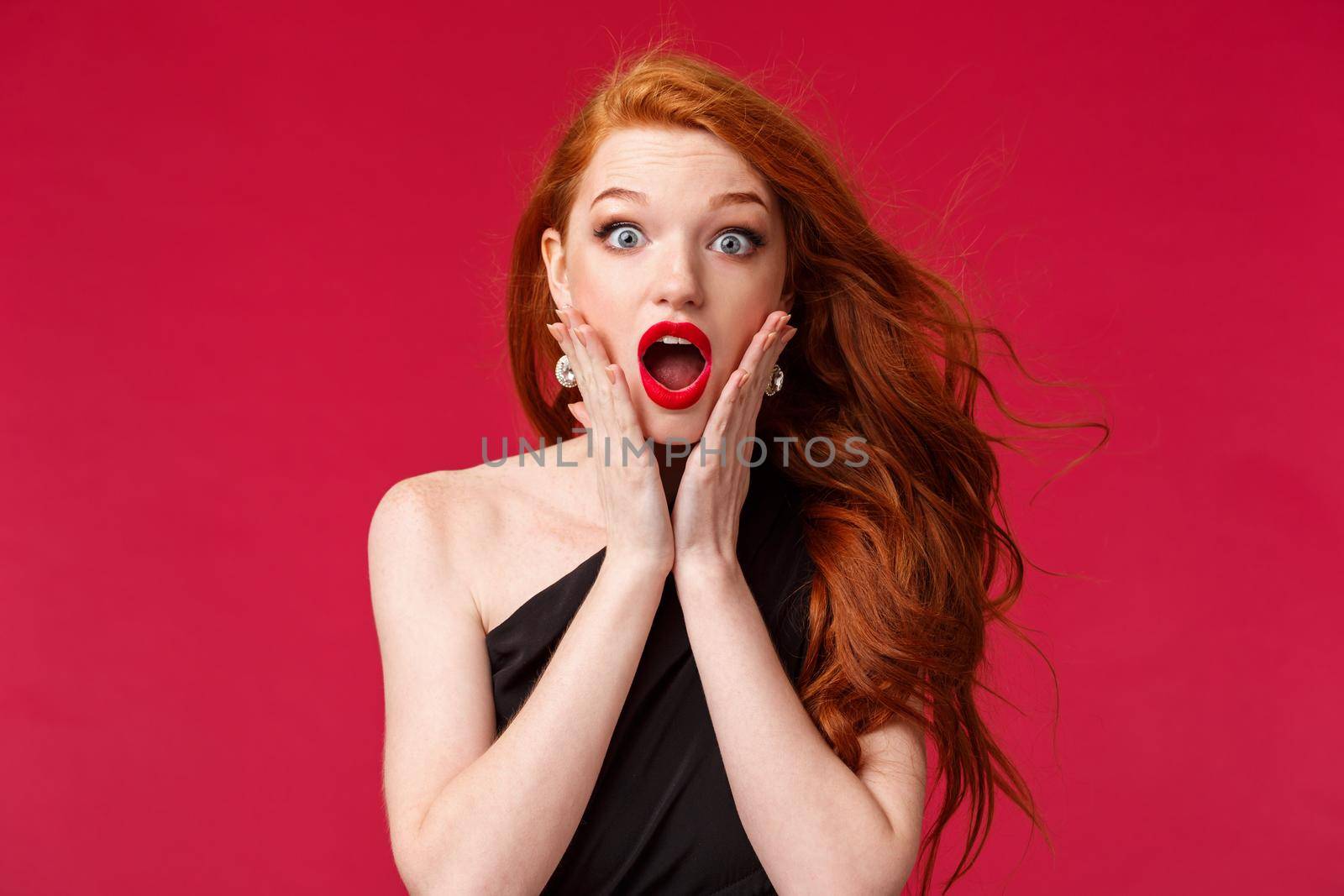 Makeup, beauty and women concept. Close-up portrait of shocked and surprised redhead woman found out surprising news, hold hands on cheeks look with compassion and amazement camera.