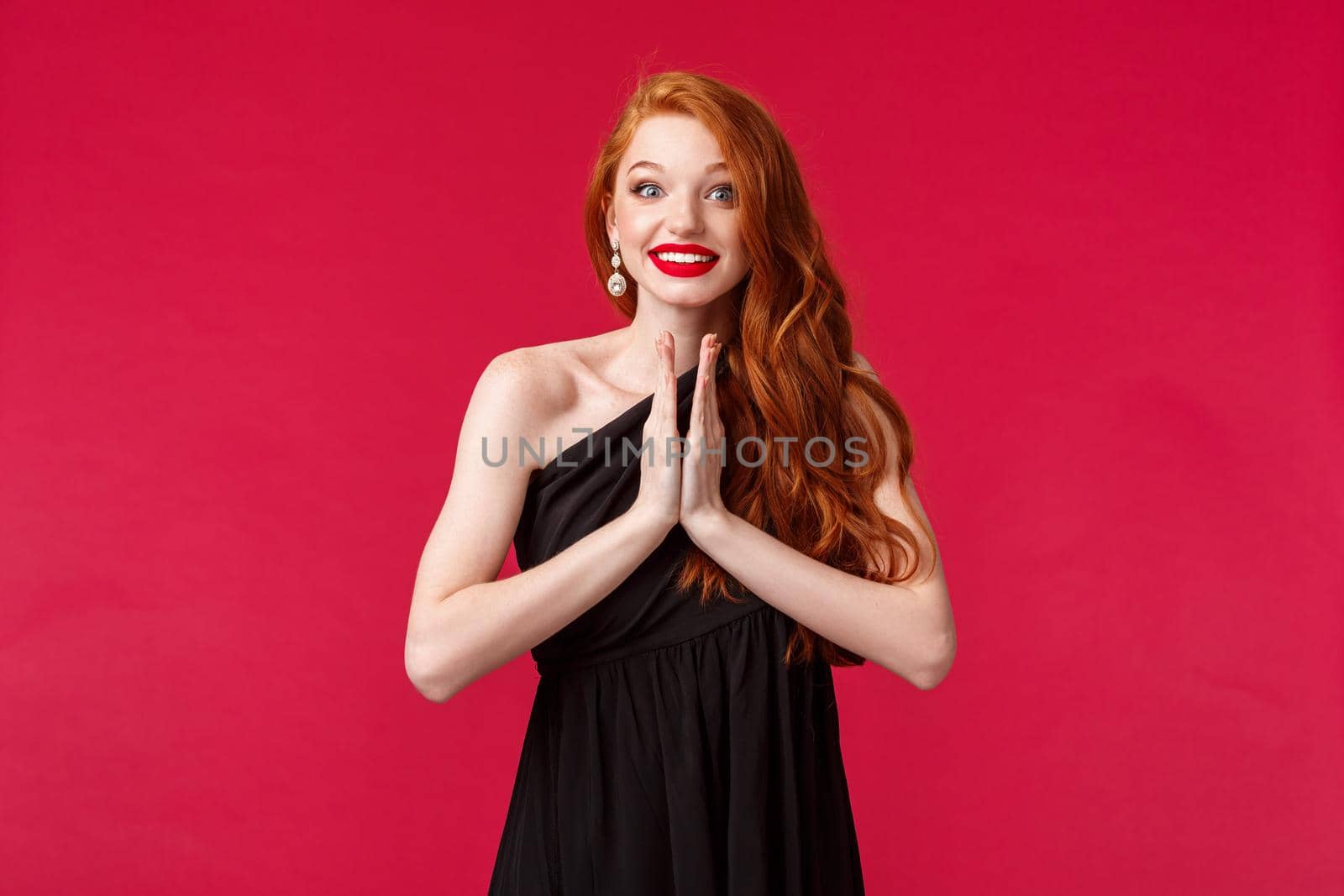 Portrait of hopeful and optimistic, excited redhead female in black dress, clap hands, applause thrilled watching stunning performance with amused smile, standing red background by Benzoix