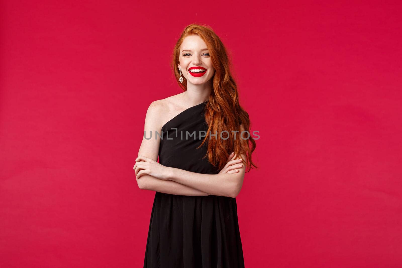 Elegance, fashion and woman concept. Portrait of elegant and sexy confident young woman with ginger hair, wear stylish black dress and makeup, laughing, cross hands chest assertive.