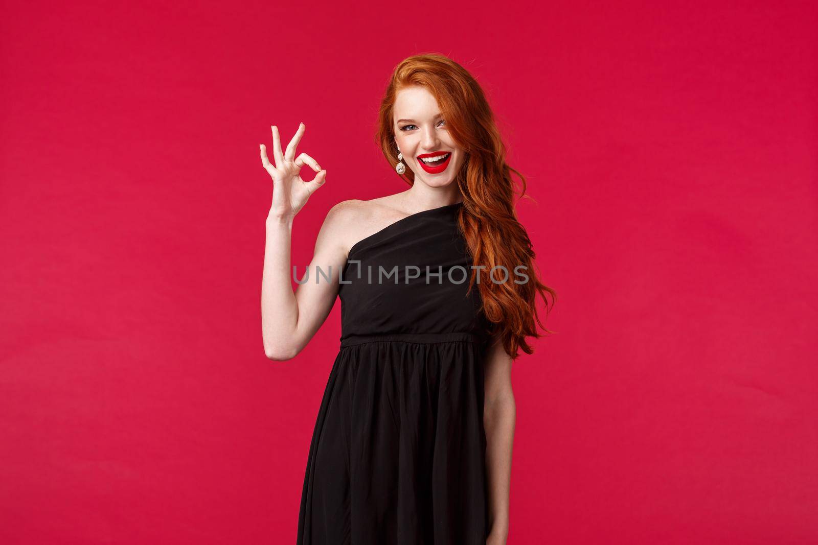 Elegance, fashion and woman concept. Portrait of sexy redhead assertive young woman in stylish elegant black dress, slim female model wearing prom outfit, show okay, excellent gesture smile pleased.