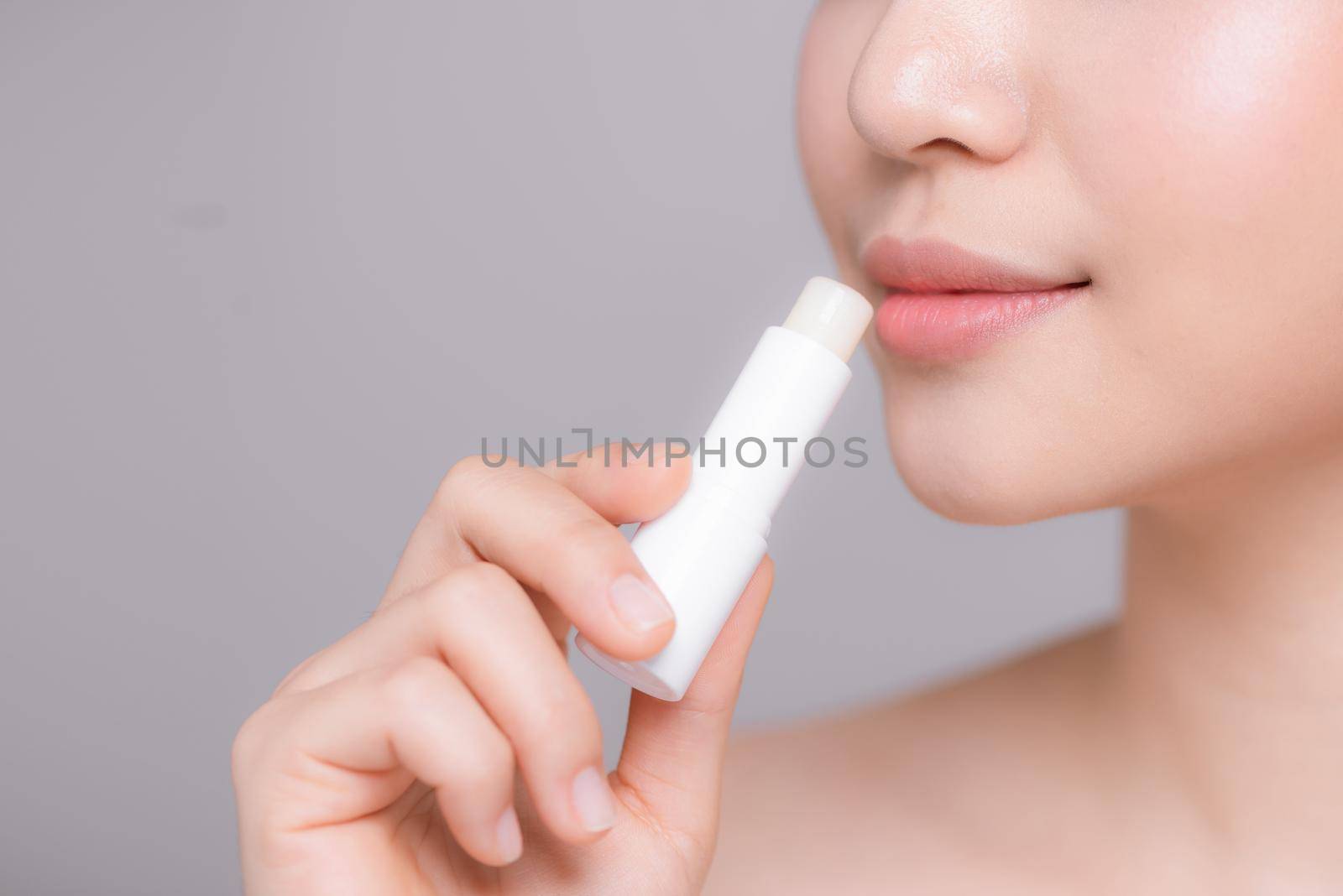 Woman With Beauty Face Applying Lip Balm.
