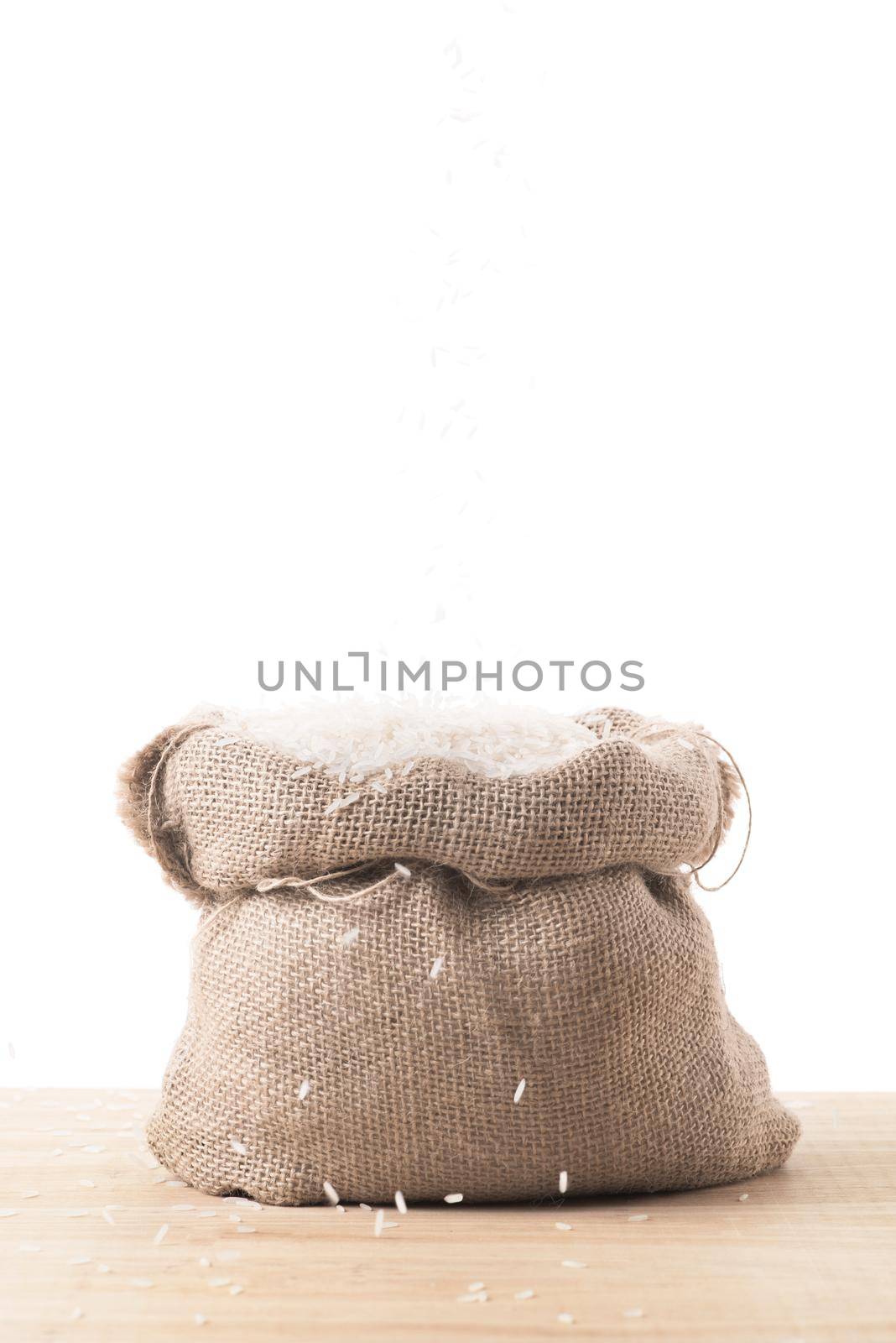 White rice in burlap sack bag isolated on white background
