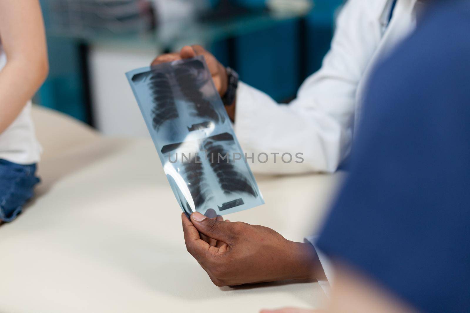 Closeup of african american pediatrician doctor holding lung radiography by DCStudio