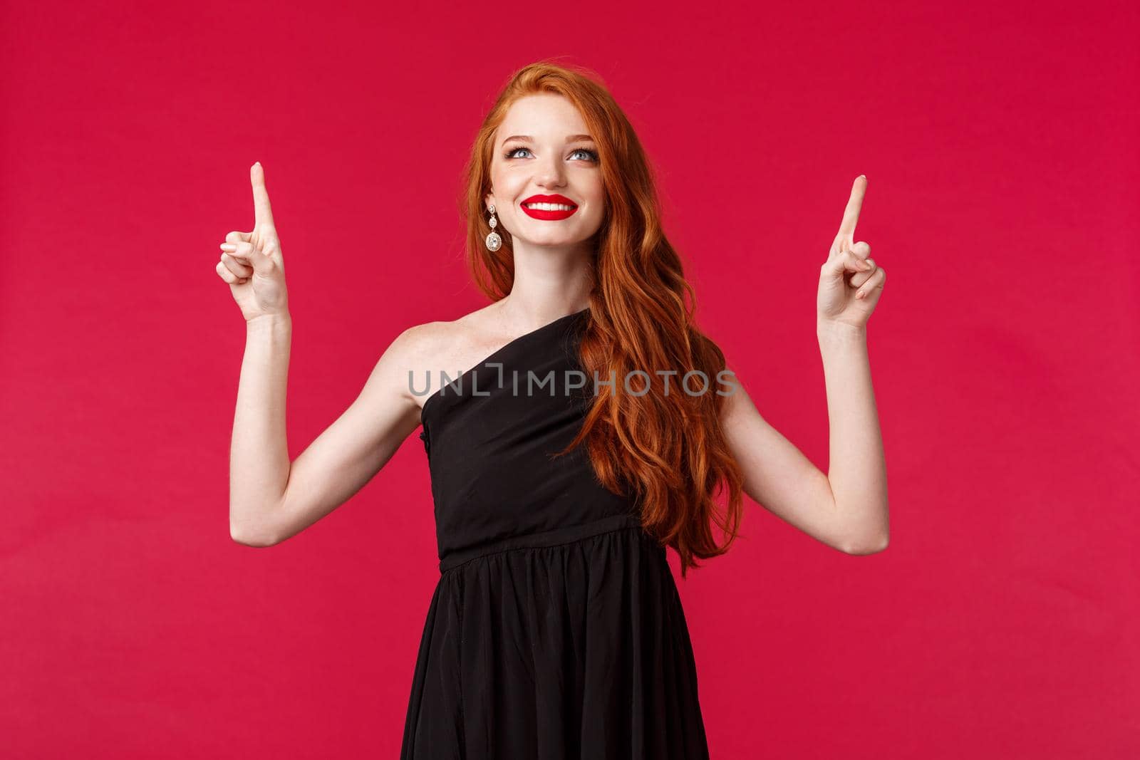 Celebration, events, fashion concept. Portrait of elegant and dreamy sensual redhead woman in black dress, pointing looking up with happy satisfied expression, found what she needs by Benzoix