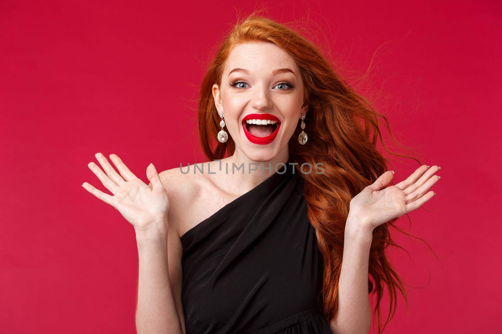 Makeup, beauty and women concept. Close-up portrait of gorgeous redhead woman happy to see someone at her party of event, clap hands surprised and pleased, standing red background.