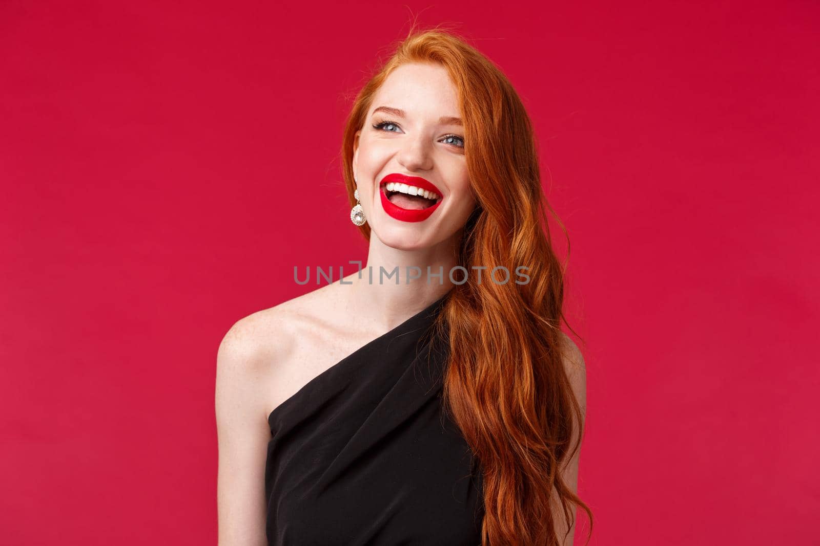 Close-up portrait dreamy beautiful redhead woman attend formal party, romantic date, enjoying having fun, smiling left and wearing black evening dress, standing red background.
