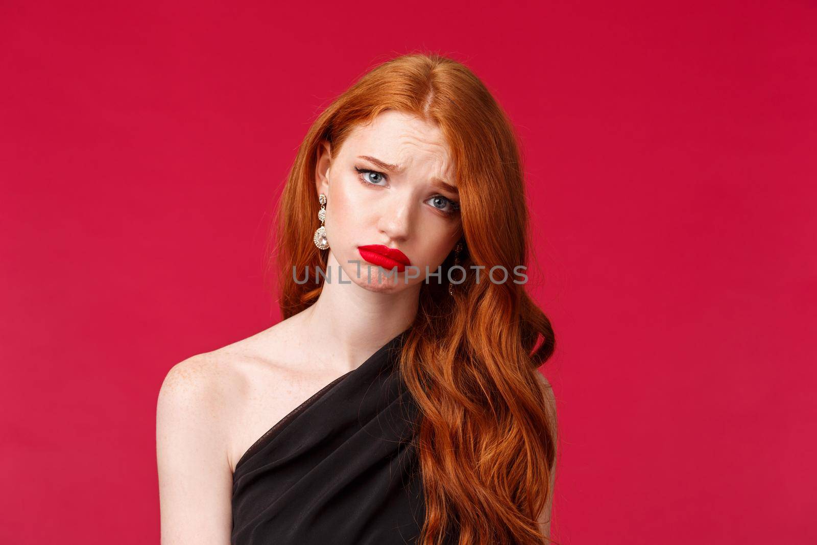Close-up portrait of gloomy and upset young redhead woman in red lip gloss, black evening dress, want to cry but have makeup on, look sadness and distress, feel let down, stand red background.