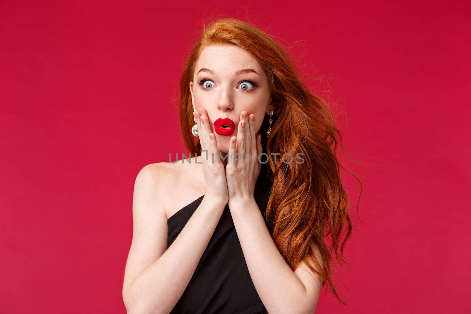 Makeup, beauty and women concept. Close-up portrait of amazed and impressed young redhead beautiful girl seeing something awesome and expensive, want it, stare astonished, standing red background.