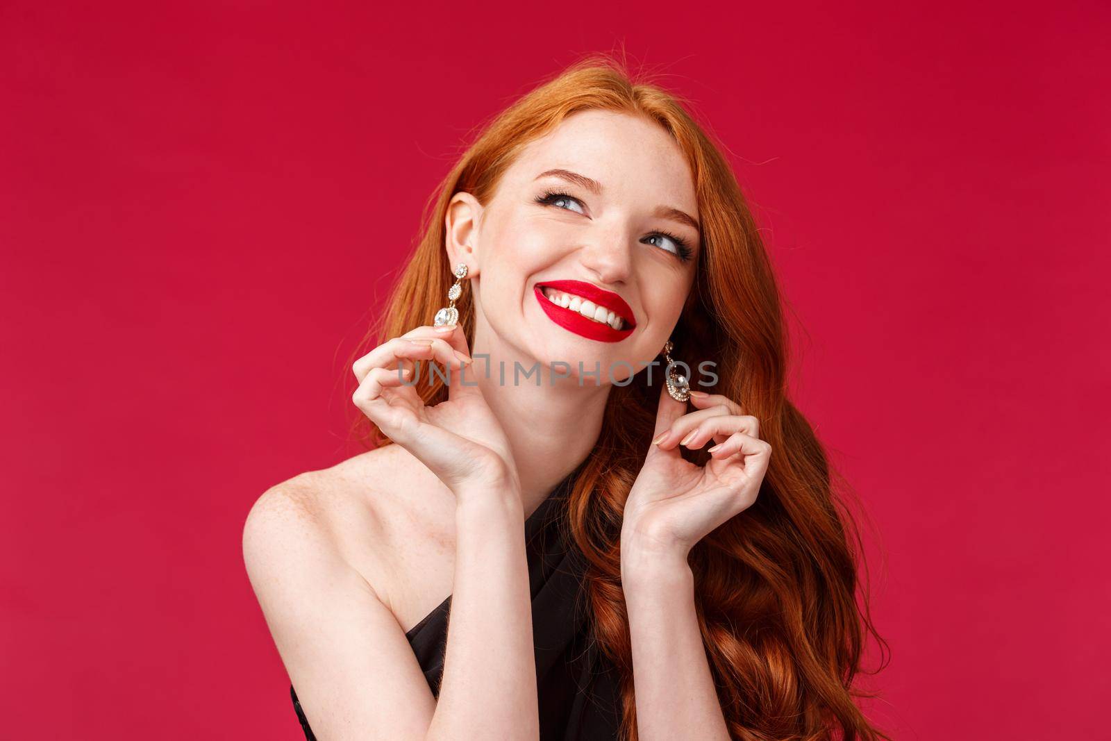 Elegance, beauty and fashion concept. Close-up portrait of feminine gorgeous young redhead woman touching her earrings look up away with beaming smile, dress for success.
