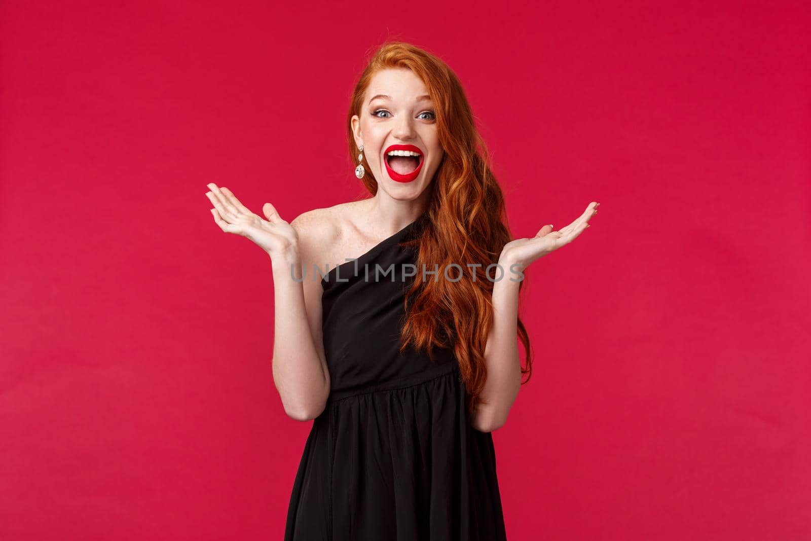 Fashion, luxury and beauty concept. What a nice surpirse. Amused and happy, excited redhead woman in elegant black dress, applause as attend awesome performance, stand red background.