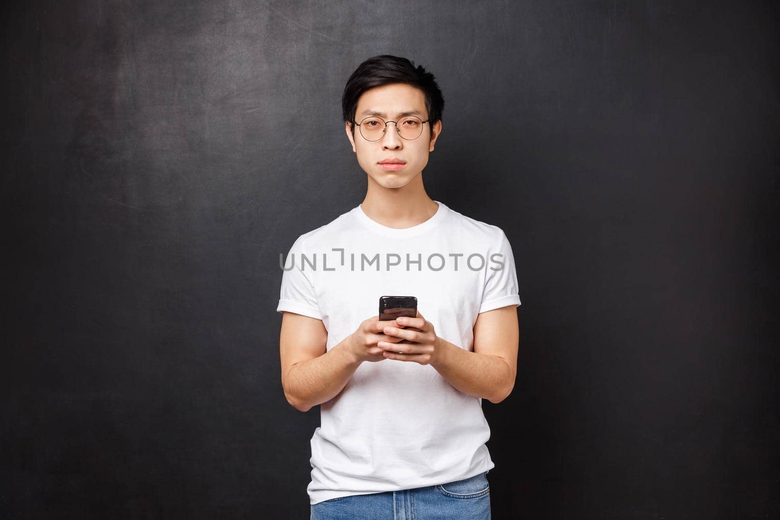 Technology, gadgets and people concept. Serious suspicious and dubious young asian guy dont believe person online telling truth, receive strange messge, squint camera uncertain, hold smartphone by Benzoix